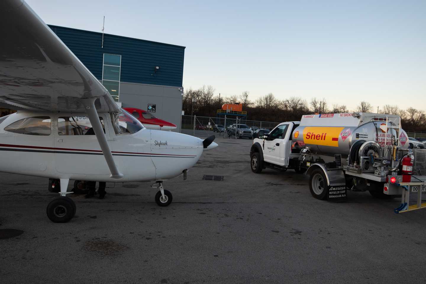 An aircraft parked on the airport ramp being fueled.